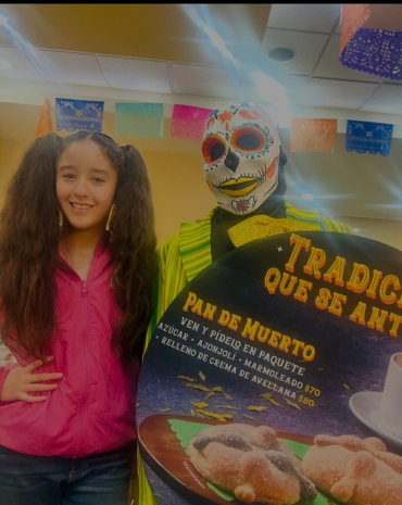 Niña feliz comiendo pan de muerto en Bisquets Obregón